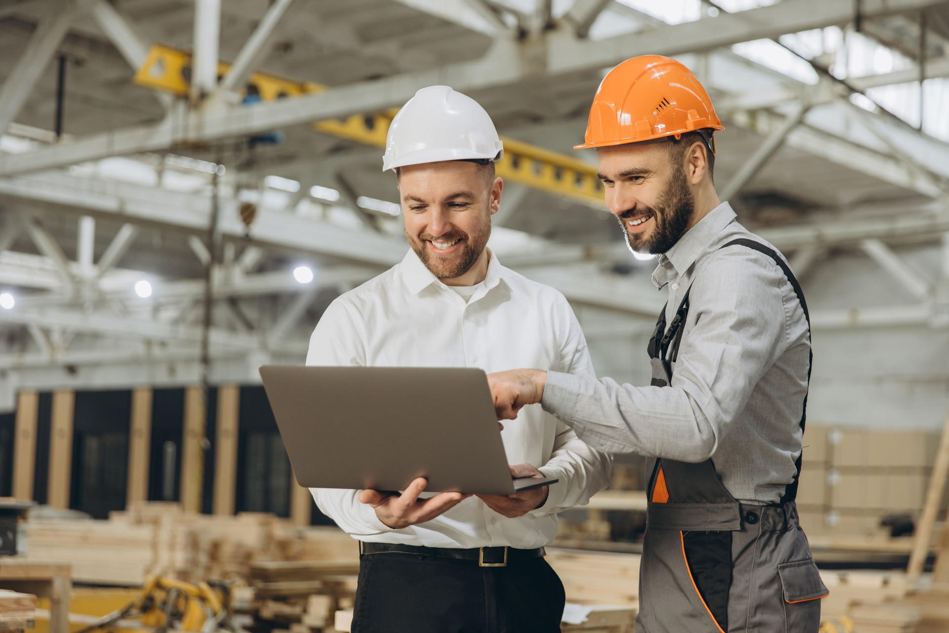 Engineers using laptop discussing project in modular building factory