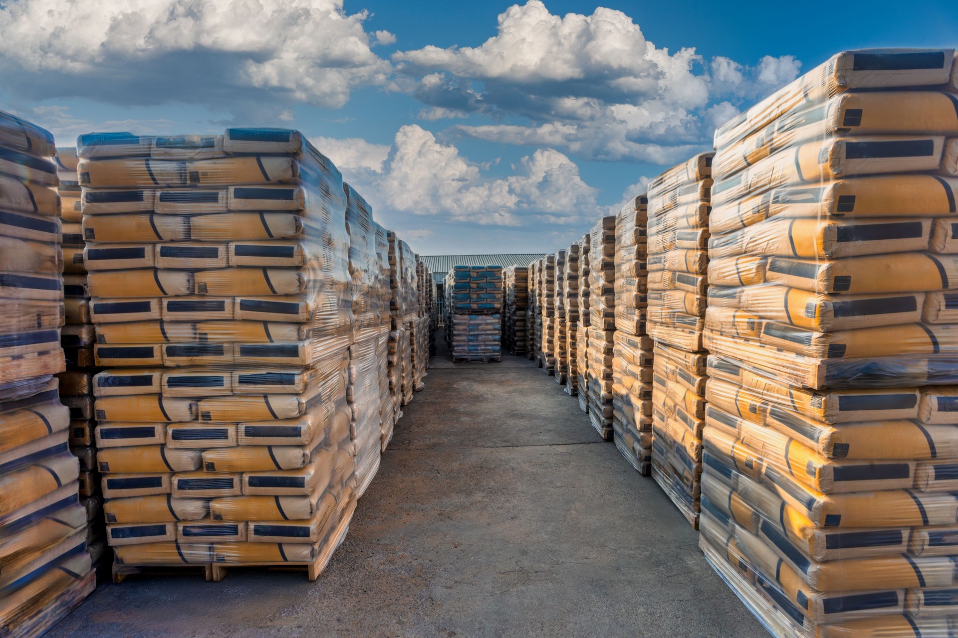 huge stack of cement paper bags stored in the yard outdoors, in a deposit